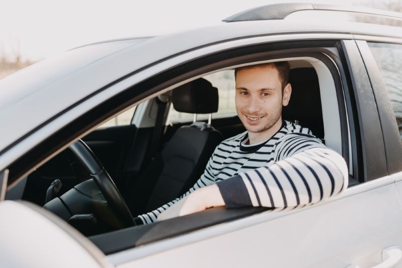 man smiling in driver's seat of car