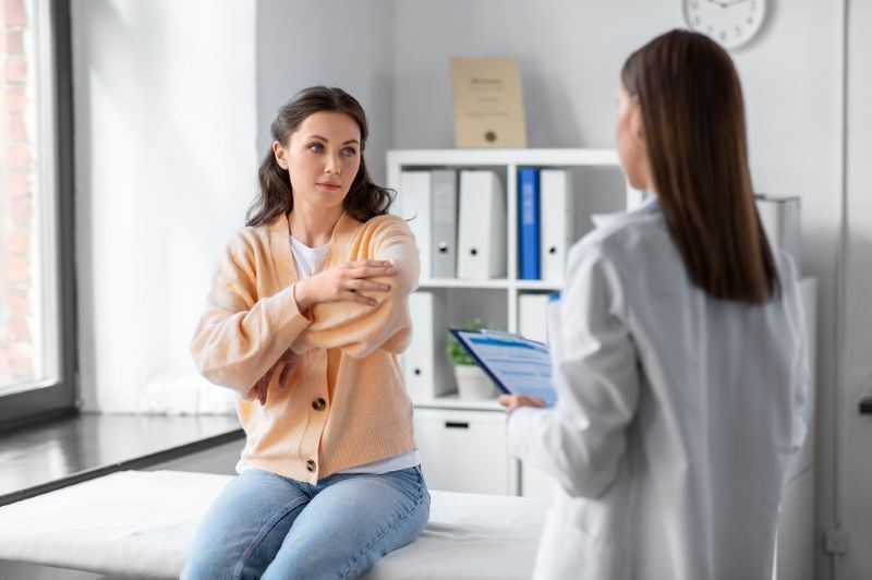 woman at doctor's office experiencing pain in her arm