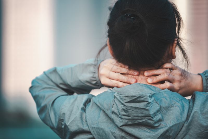 Woman grabbing the back of her neck in discomfort