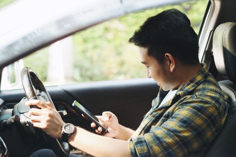 A man using his phone while driving his car