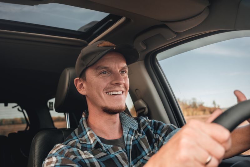 Smiling man driving pickup truck during the day