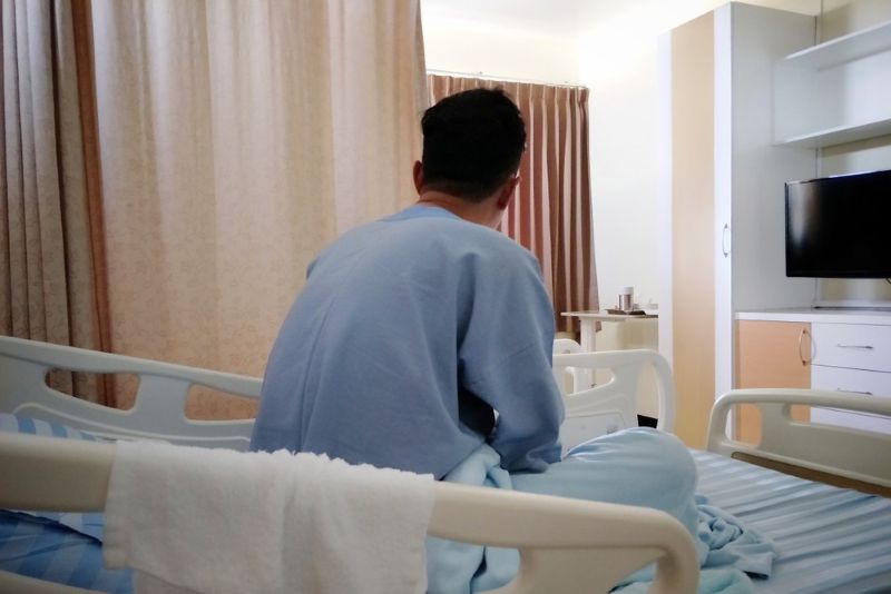 Injured man sitting upright in hospital bed